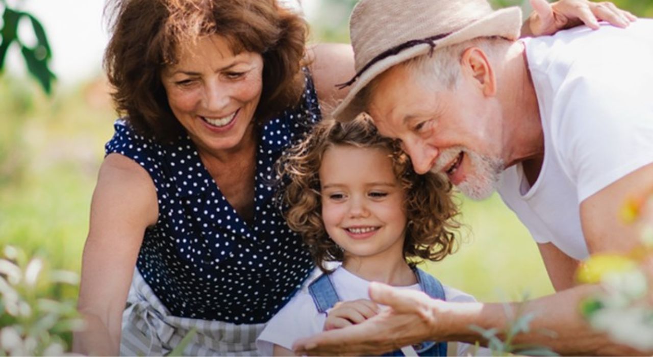 Retirement-villages-in-England-new-build-incentives-Burnham-Waters-Essex-retired-couple-in-garden-with-granddaughter