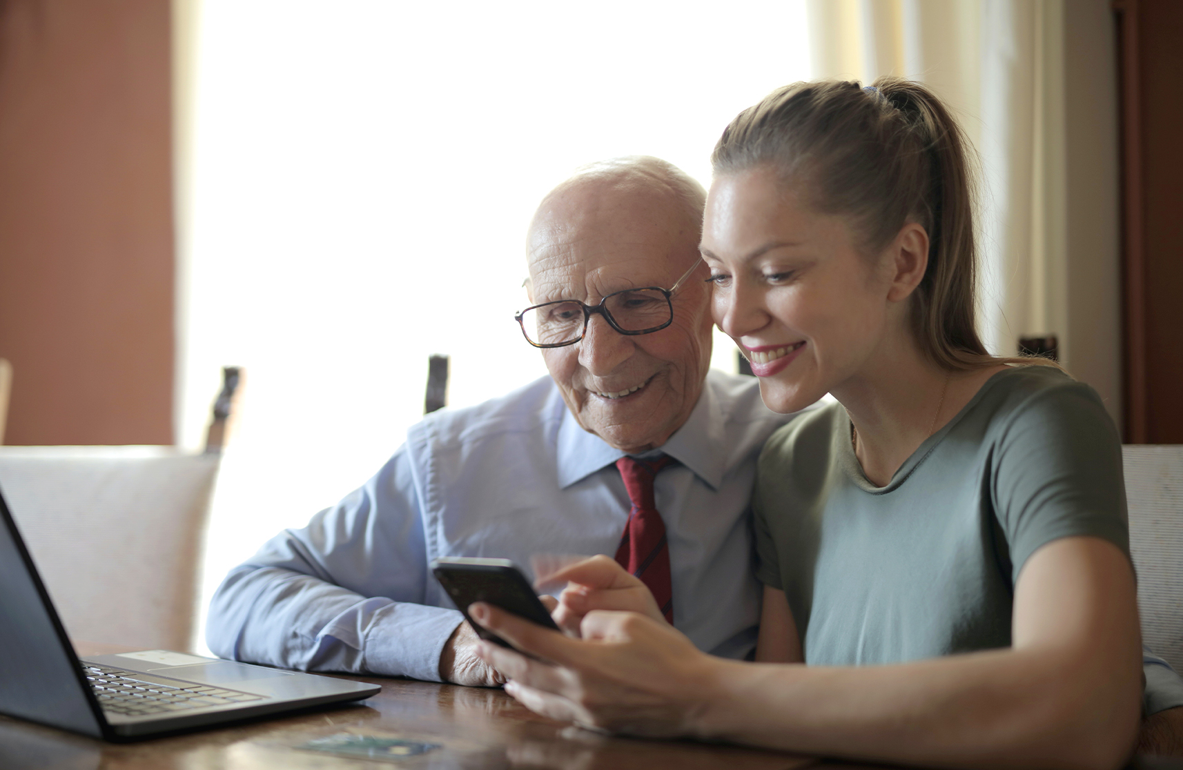 An image of a grandchild showing their grandpa how to use a phone in retirement homes in Essex.