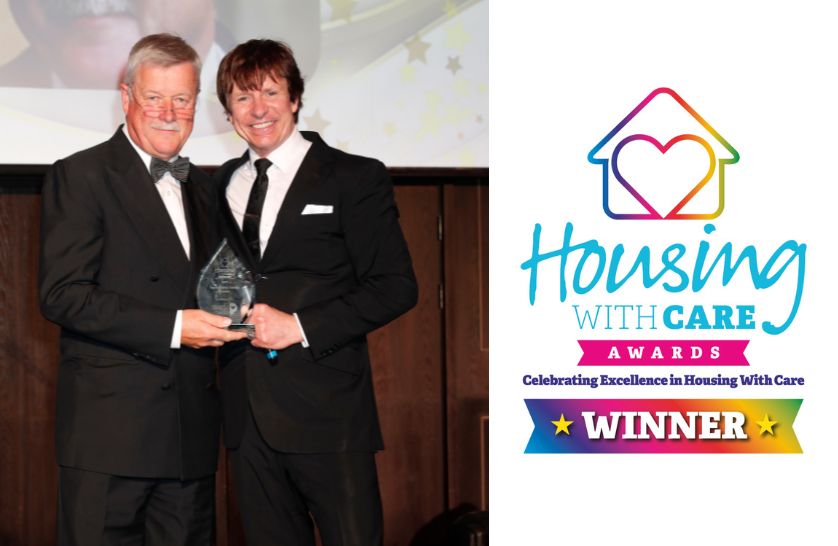 Ian Holloway from Burnham Waters on stage collecting an award at the Housing with Care Awards 2025