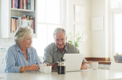 Older couple looking at laptop as latest technology supports independent living at Burnham Waters 