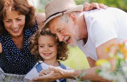 Retirement-villages-in-England-new-build-incentives-Burnham-Waters-Essex-retired-couple-in-garden-with-granddaughter