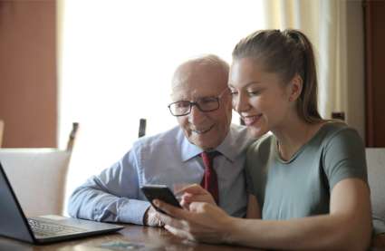 An image of a grandchild showing their grandpa how to use a phone in retirement homes in Essex.